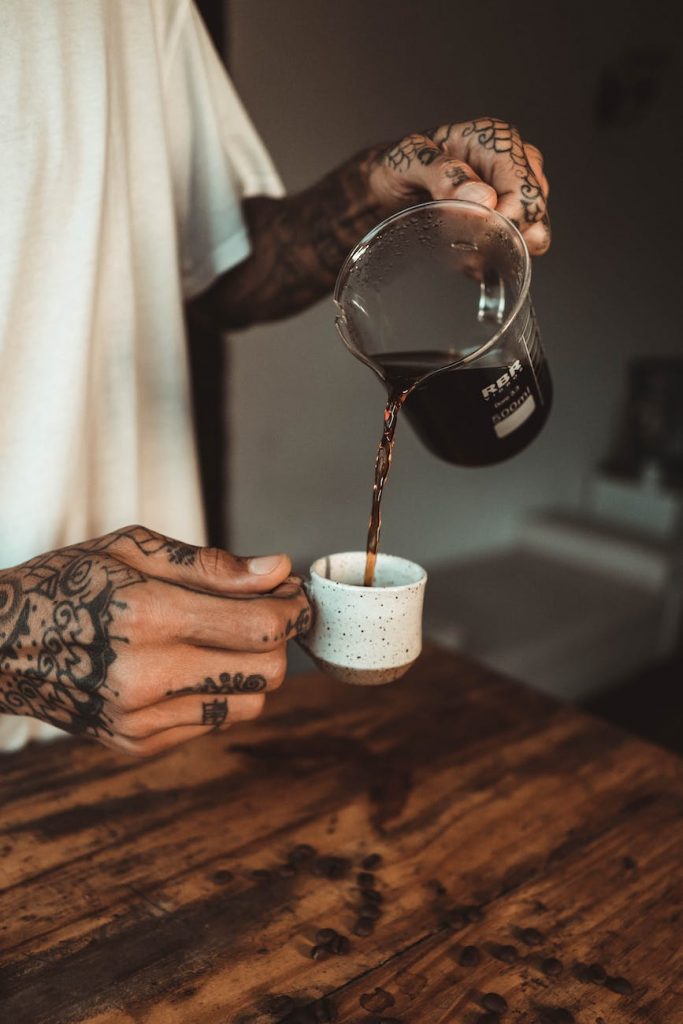 person pouring coffee on white ceramic cup