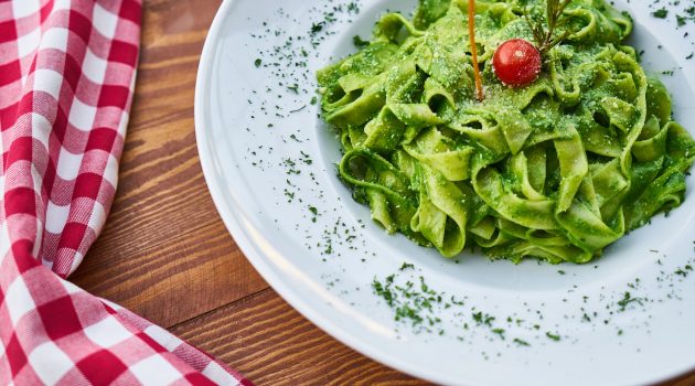 flat pasta noodle with green sauce dish and cherry tomato on top