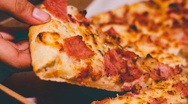 close up photo of person holding pizza