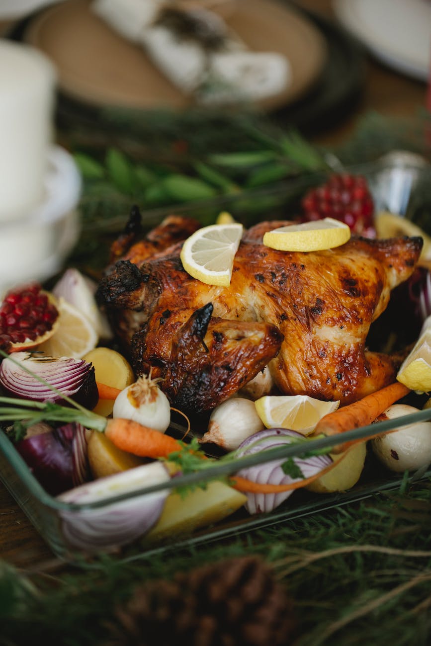 roasted chicken with vegetables in glass roaster on table with fir sprigs