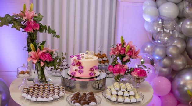 birthday cake and sweets on a table decorated with flowers and balloons