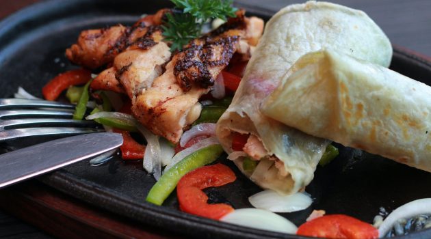 meats and vegetables on black oval sizzling plate