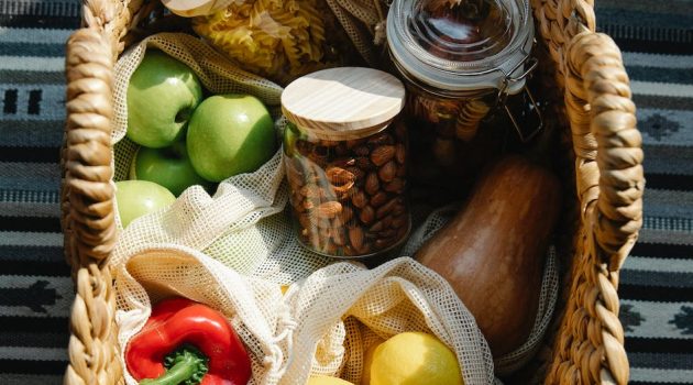 wicker basket with vegetables and products placed on table in sunny day