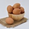 brown eggs on brown wooden bowl on beige knit textile